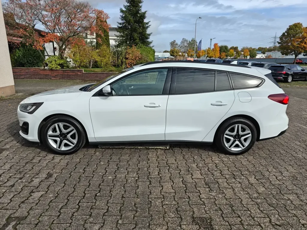 Weißer Ford Focus Cool Klima LED Shz PDC Airplay Winterpaket Kombi von der Seite, mit schwarzen Fensterrahmen und fünf Speichen Alufelgen.