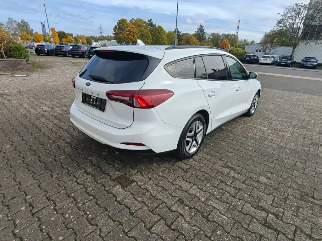 Weißer Ford Focus Cool Klima LED Shz PDC Airplay Winterpaket Kombi von hinten rechts, geparkter Zustand.