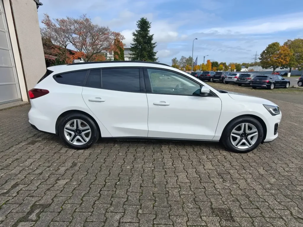 Ford Focus Cool Klima LED Shz PDC Airplay Winterpaket, weißer Kombi von der Seite, getönte Scheiben, Alufelgen.