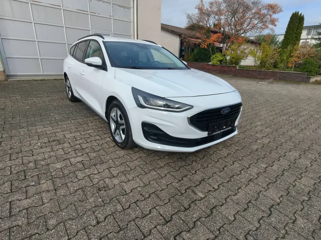 Weißer Ford Focus Cool Klima LED Shz PDC Airplay Winterpaket Kombi von vorne rechts, geparkt.