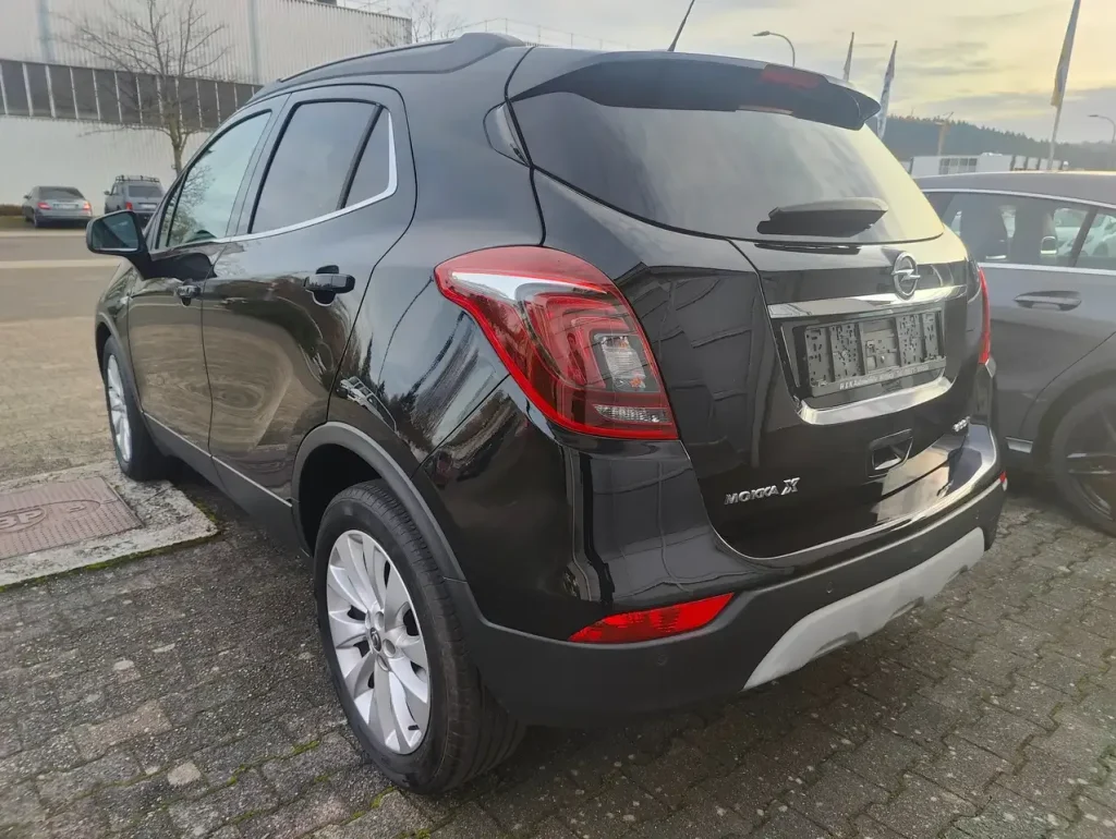 Opel Mokka X Innovation Start/Stop in Schwarz, Heck- und Seitenansicht, mit Rückleuchten und silberner Dachreling.