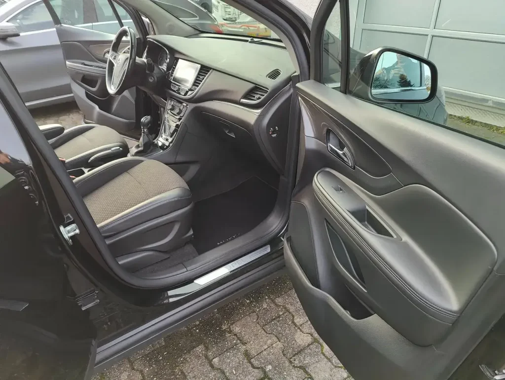 Innenraum mit Fahrersitz, Lenkrad, Mittelkonsole und geöffneter Fahrertür des Opel Mokka X Innovation Start/Stop