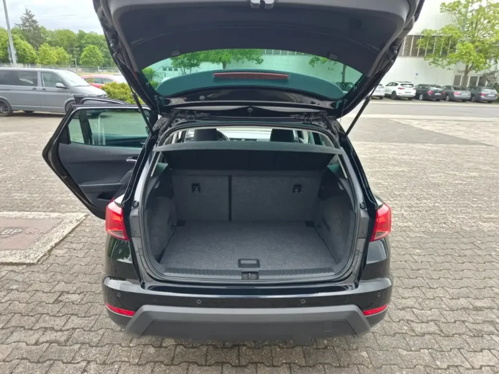 Kofferraum mit geöffneter Heckklappe und geöffneter linker Fondtür des schwarzen SEAT Arona Style.