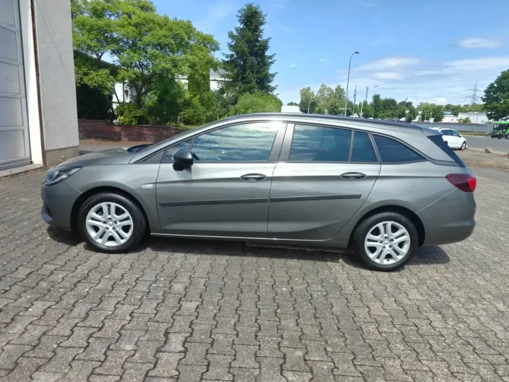 Opel Astra Edition Start/Stop Winterpaket 1.Hd Navi Kombi in Grau von der Seite, mit schwarzen Türgriffen und silbernen Felgen.