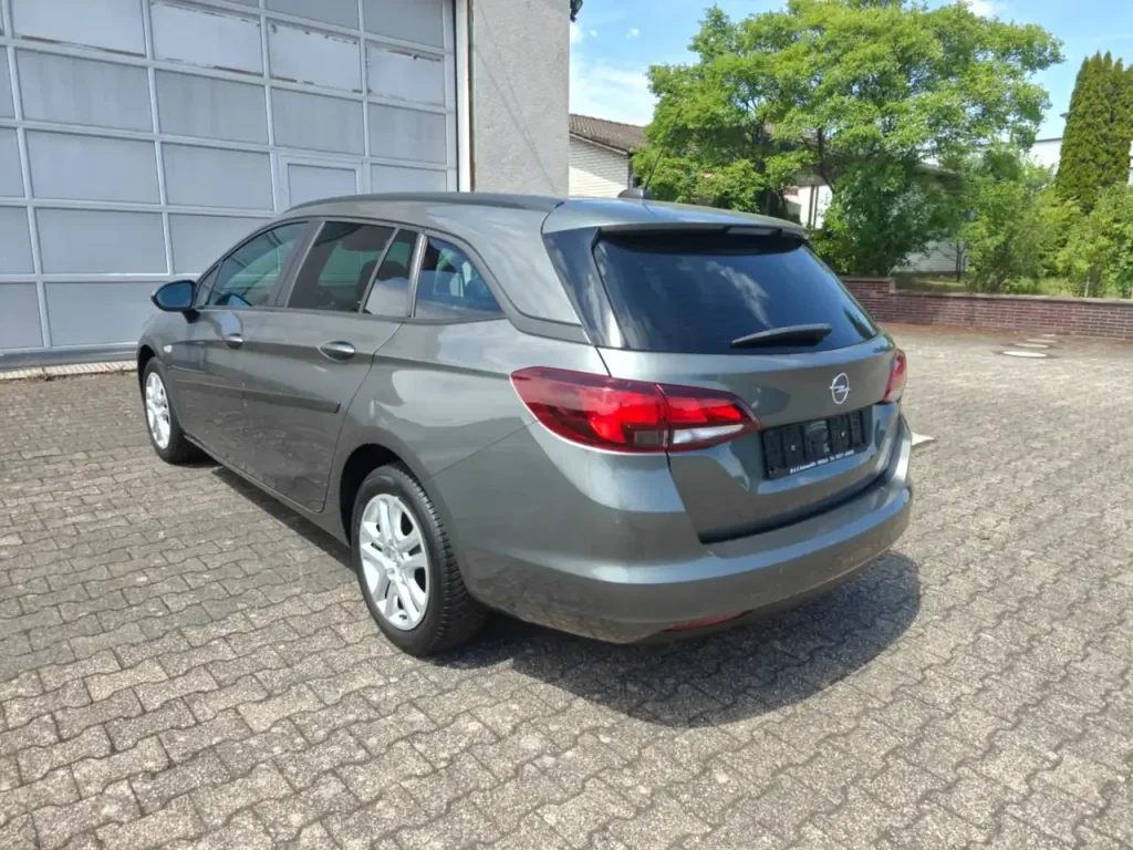 Opel Astra Edition Start/Stop Winterpaket 1.Hd Navi, grauer Kombi von hinten rechts, getönte Heckscheibe, Rückleuchten sichtbar
