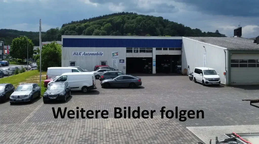 Schriftzug „Weitere Bilder folgen“ vor einem Autohaus mit mehreren geparkten Fahrzeugen, kein Audi Q2 sport S-Line sichtbar.