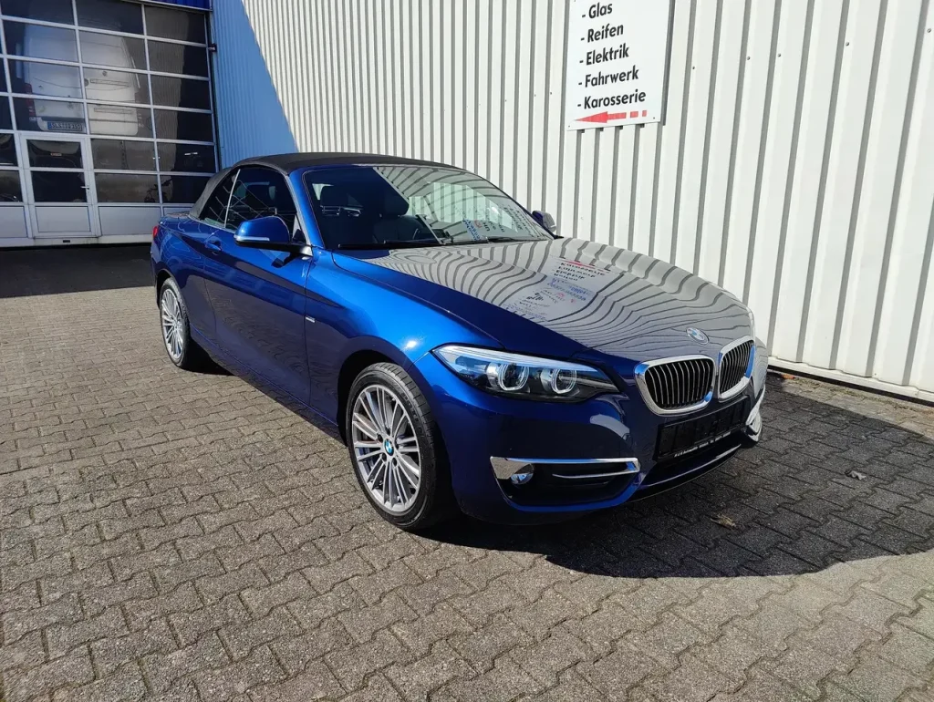 BMW 218 218 i Luxury Line LED Leder Alu Shz PDC, blauer Cabrio mit schwarzem Verdeck, Front- und Seitenansicht.