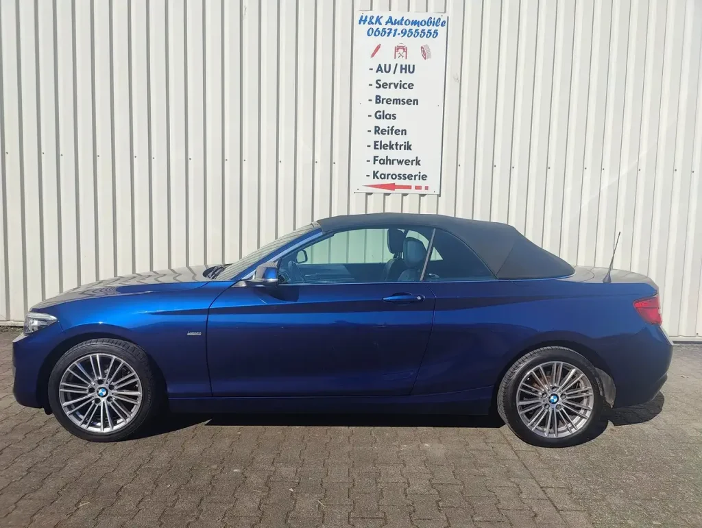 BMW 218 218 i Luxury Line LED Leder Alu Shz PDC, blaues Cabrio mit geschlossenem schwarzem Verdeck, Seitenansicht, Alufelgen, LED-Scheinwerfer.