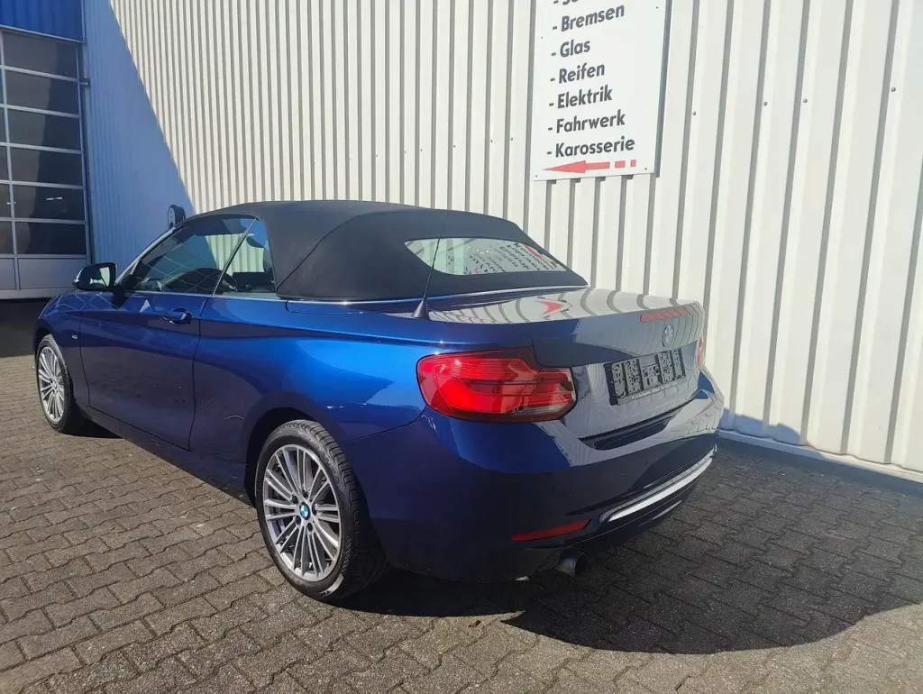 BMW 218 218 i Luxury Line LED Leder Alu Shz PDC, blauer Cabrio mit geschlossenem schwarzem Verdeck, Heck- und Seitenansicht, Alufelgen.