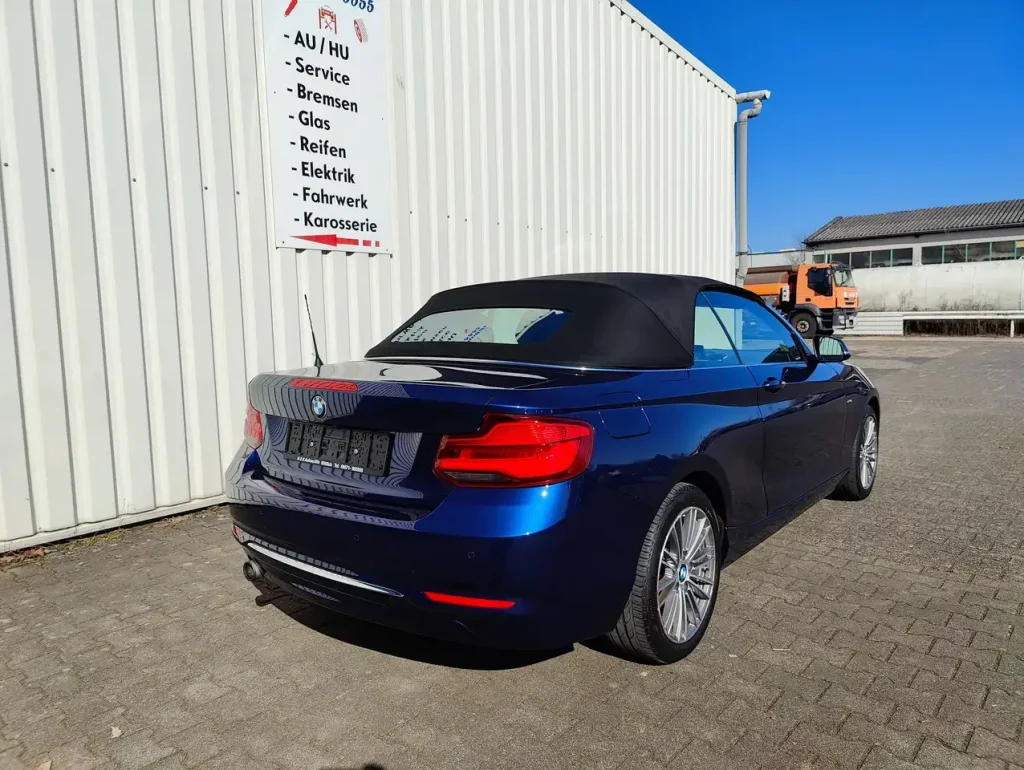 BMW 218 218 i Luxury Line LED Leder Alu Shz PDC, blaue Cabrio-Heckansicht mit schwarzem Verdeck und Alufelgen