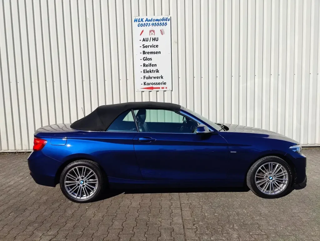 BMW 218 218 i Luxury Line LED Leder Alu Shz PDC Cabrio in Blau mit geschlossenem schwarzem Verdeck, Seitenansicht, Alufelgen.