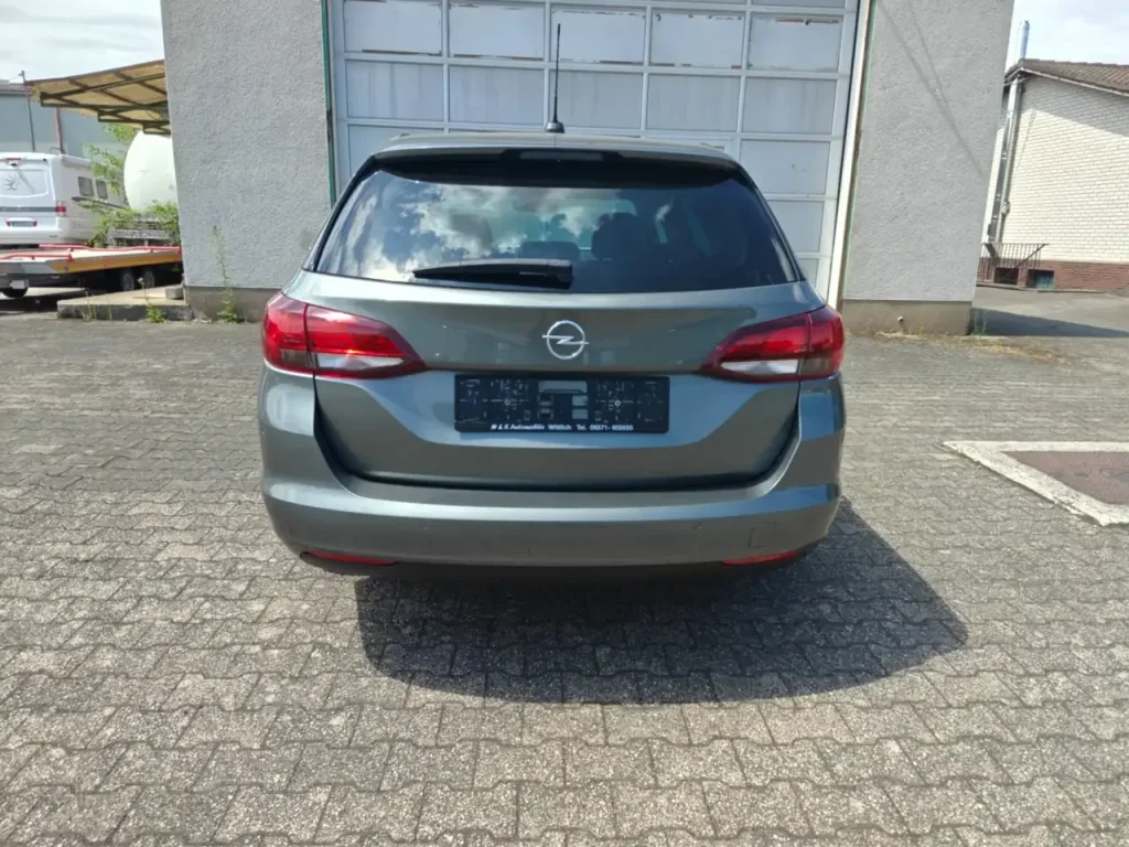 Heckansicht grauer Opel Astra Edition Start/Stop Winterpaket 1.Hd Navi mit geschlossenem Kofferraum und sichtbarem Opel-Logo.
